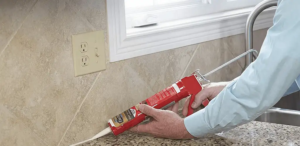 Handyman applying caulk along a kitchen backsplash and countertop seam in Little Rock, AR