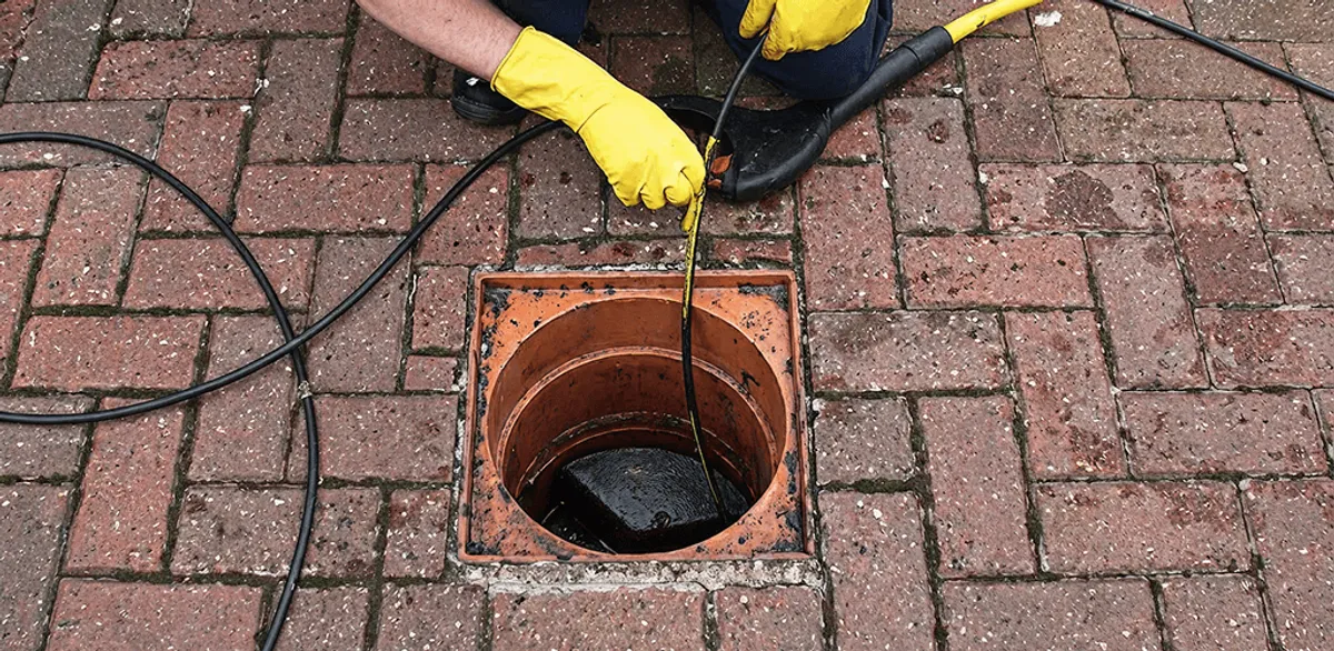 Drain cleaning technician using a drain snake to clear a clogged drain in Little Rock, AR