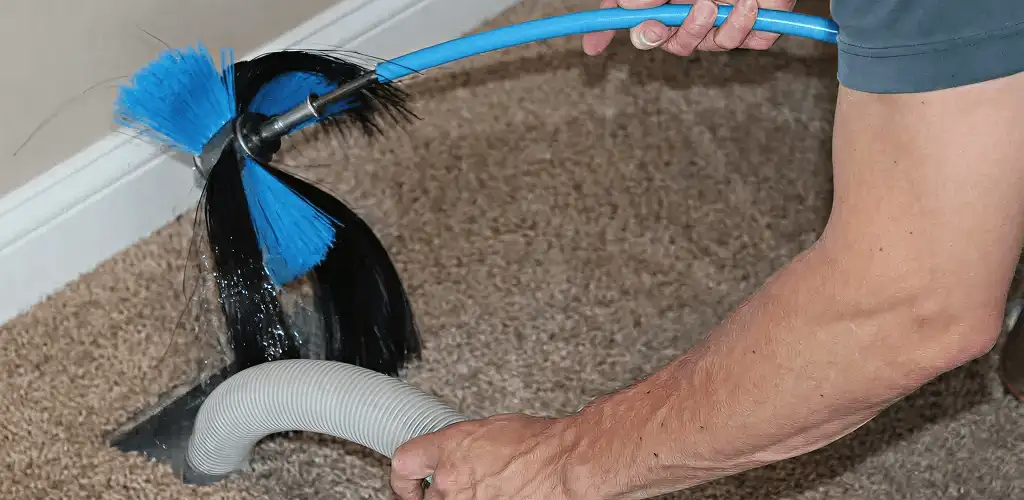 Dryer vent cleaning technician brushing lint from a vent line in Little Rock, AR