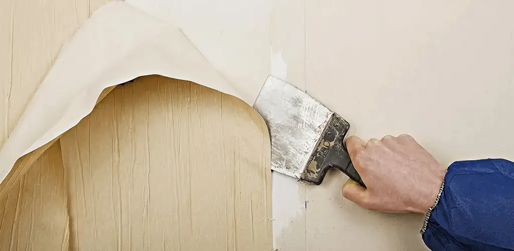 Handyman removing wallpaper with a scraper for wall preparation in Little Rock, AR