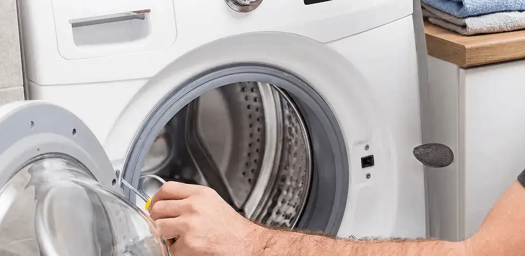 Handyman repairing a front-load washing machine and inspecting the drum in Little Rock, AR