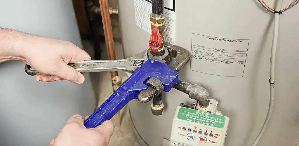 Water heater repair technician tightening the shutoff valve and supply line in Little Rock, AR